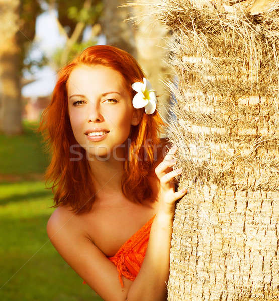 look out from behind a palm tree, closeup portrait of cute girl