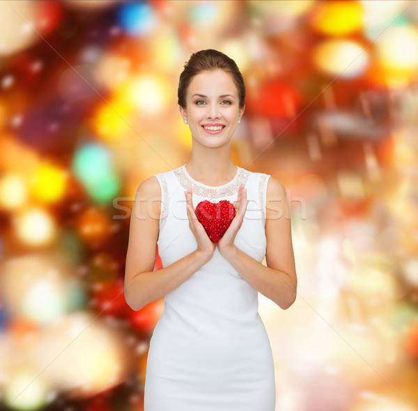 smiling woman in white dress with red heart