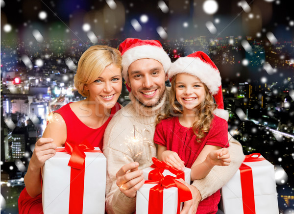 happy mother, father and little girl in santa helper hats with