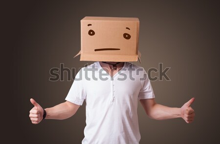 young man gesturing with a cardboard box on his head with straig