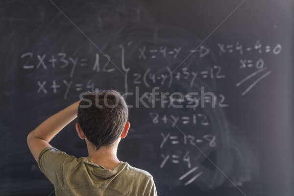 Schoolboy solving a problem on a blackboard. Stock photo © 2Design