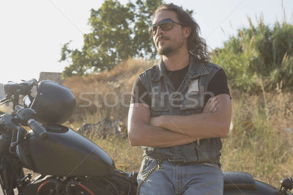 Long-haired brunette guy posing on a black custom motorcycle Stock photo © 2Design