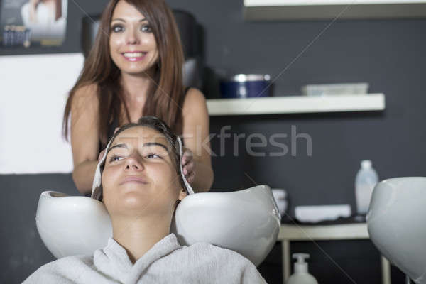 Stock photo: Portait of a young Hairdresser washing hair of a client 