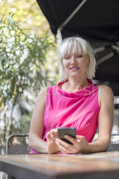 Mature blonde hair woman using a mobile phone outdoors Stock photo © 2Design