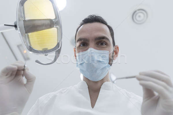 Dentist wearing surgical mask while holding angled mirror and dr Stock photo © 2Design