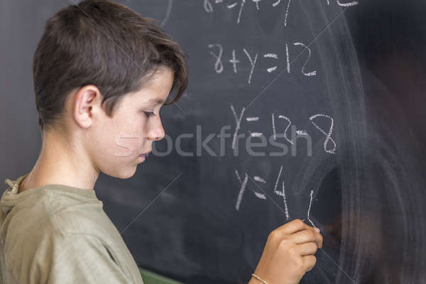 Schoolboy solving a problem on a blackboard. Stock photo © 2Design