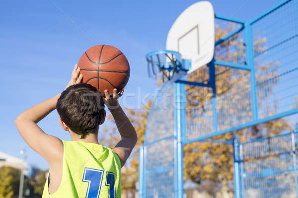 teenager throwing a basketball into the hoop from behind Stock photo © 2Design