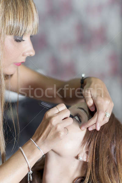 Young makeup artist doing makeover to pretty model Stock photo © 2Design