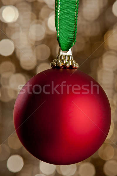 Stock photo: Single Christmas bauble in front of a gold glitter background