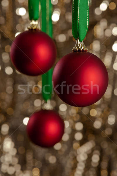 Three red Christmas baubles in front of a gold glitter backgroun Stock photo © 3523studio