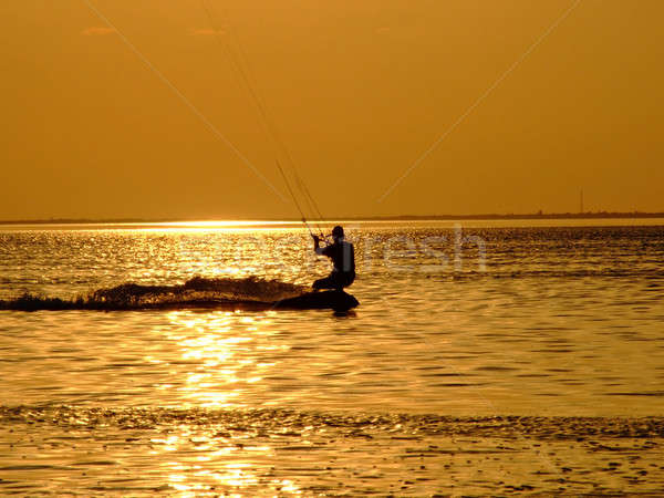 Silhouette of a kite-surf on waves of a gulf on a sunset 1 Stock photo © acidgrey