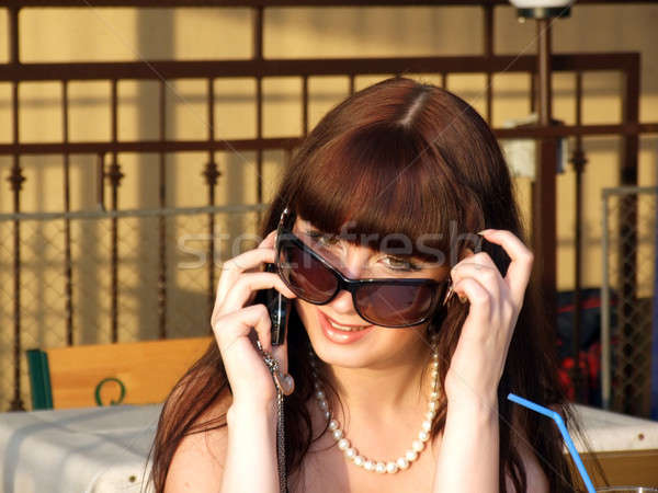 A smiling girl in sunglasses talks by a mobile phone2 Stock photo © acidgrey