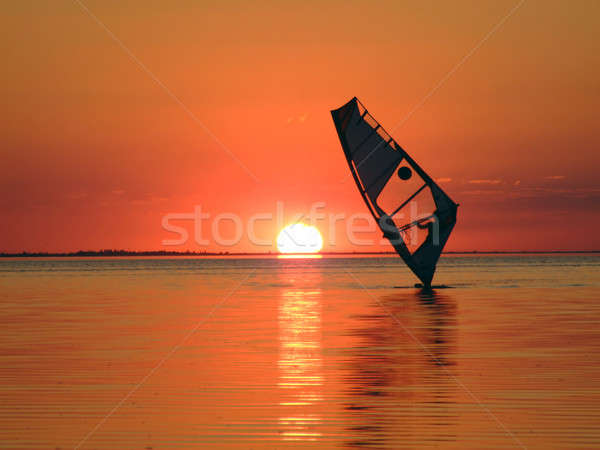 Silhouette of a windsurfer on waves of a gulf on a sunset 1 Stock photo © acidgrey