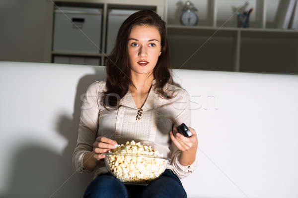 Młoda kobieta oglądania telewizja kanapie jedzenie popcorn Zdjęcia stock © adam121