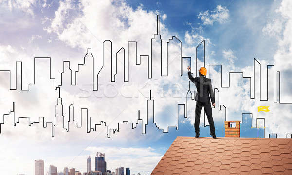 Man architect draw silhouette of modern city on blue sky. Mixed media Stock photo © adam121