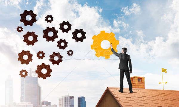 Businessman standing with back on house brick roof and drawing. Mixed media Stock photo © adam121