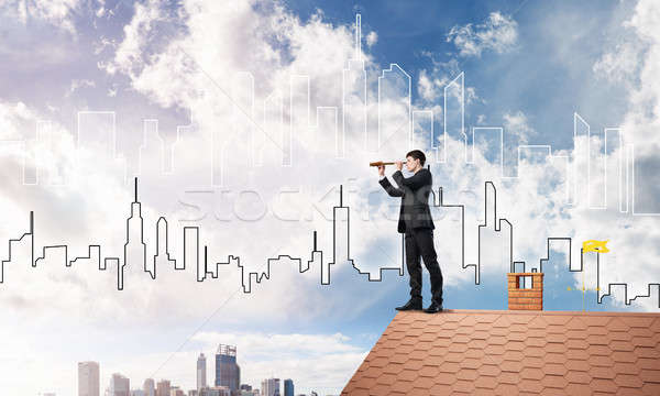 Stock photo: Engineer man standing on roof and looking in spyglass. Mixed media