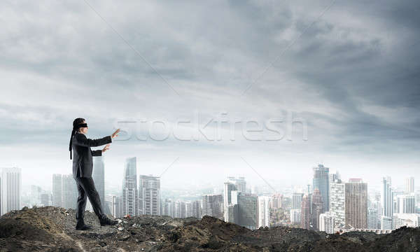 Young businessman in blindfold walking carefully and cityscape at background Stock photo © adam121