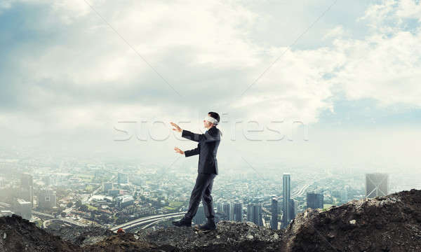 Young businessman in blindfold walking carefully and cityscape a Stock photo © adam121