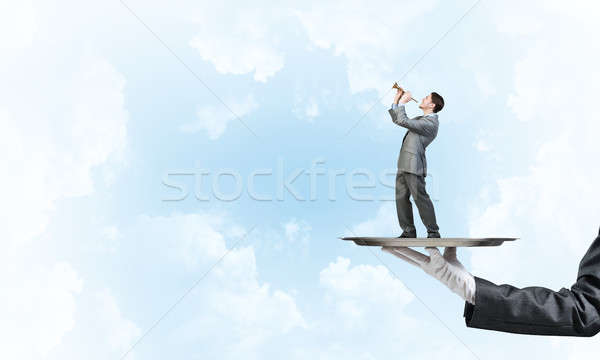 Businessman on metal tray playing fife against blue sky background Stock photo © adam121