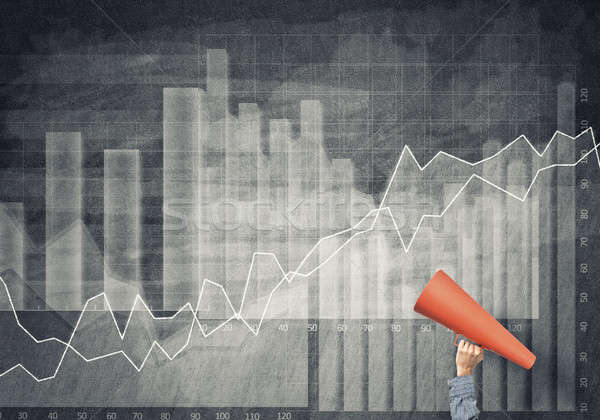 Stock photo: Hand of man holding red paper trumpet against graphs background