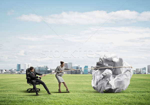 Businesspeople pulling with effort big crumpled ball of paper as Stock photo © adam121