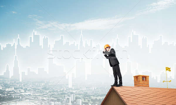 Stock photo: Engineer man standing on roof and looking in binoculars. Mixed media