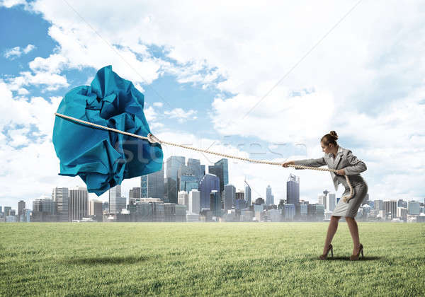 Woman pulling with effort big crumpled ball of paper as creativity sign Stock photo © adam121