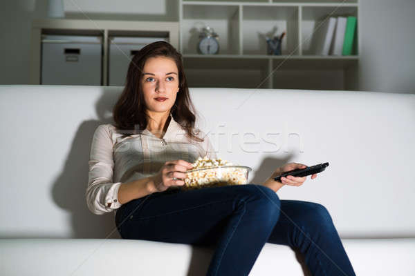 Młoda kobieta oglądania telewizja kanapie jedzenie popcorn Zdjęcia stock © adam121