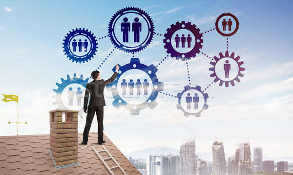 Businessman on house roof presenting teamwork and connection concept. Mixed media Stock photo © adam121