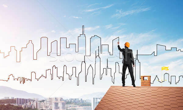 Man architect draw silhouette of modern city on blue sky. Mixed media Stock photo © adam121