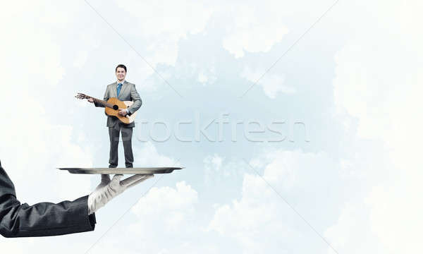 Businessman on metal tray playing acoustic guitar against blue sky background Stock photo © adam121