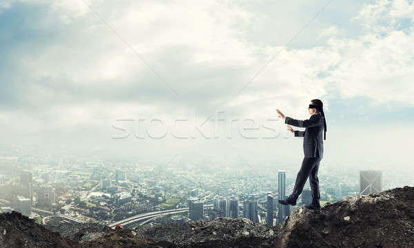 Young businessman in blindfold walking carefully and cityscape a Stock photo © adam121