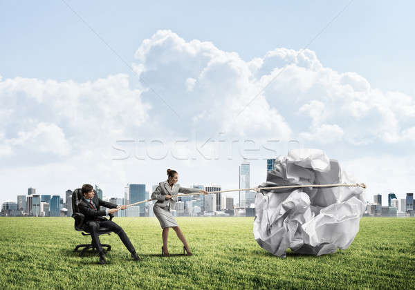 Businesspeople pulling with effort big crumpled ball of paper as Stock photo © adam121