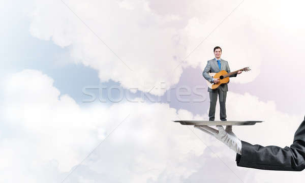 Businessman on metal tray playing acoustic guitar against blue sky background Stock photo © adam121