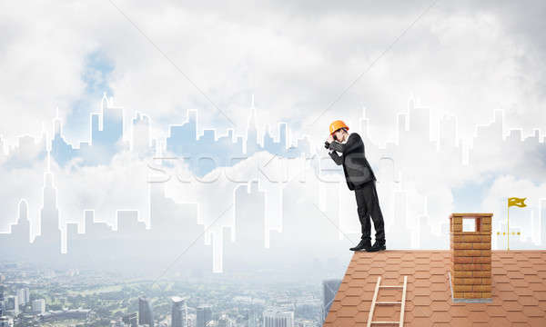Engineer man standing on roof and looking in binoculars. Mixed media Stock photo © adam121