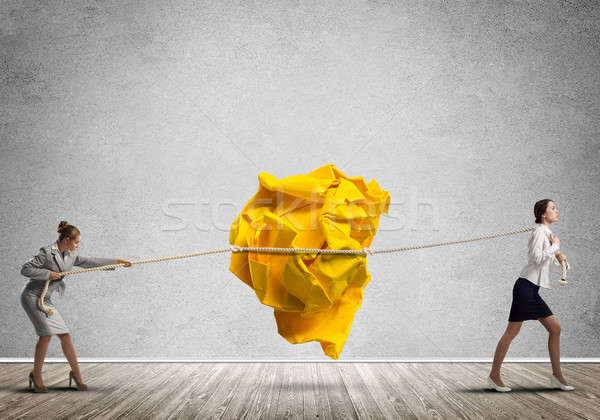 Two women pulling with effort big crumpled ball of paper as creativity sign Stock photo © adam121