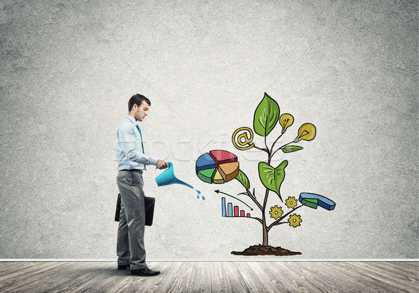 Stock photo: Young businessman in empty room watering drawn growth concept wi