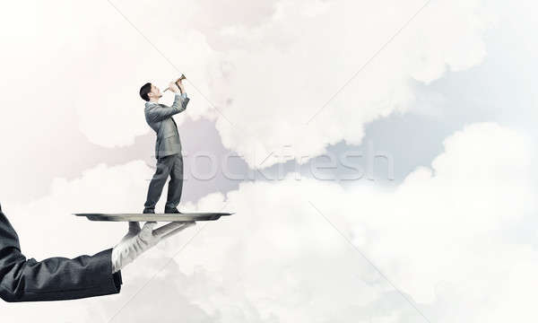 Businessman on metal tray playing fife against blue sky backgrou Stock photo © adam121