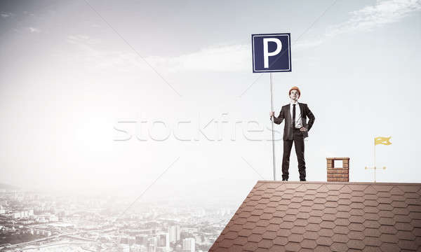 Young businessman with parking sign standing on brick roof. Mixe Stock photo © adam121
