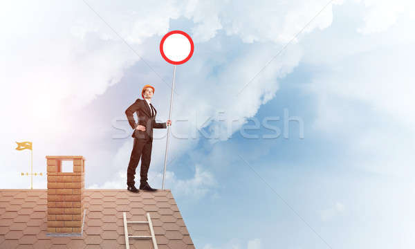 Caucasian businessman on brick house roof showing stop road sign. Mixed media Stock photo © adam121