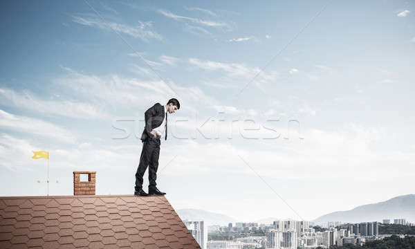 Businessman looking down from roof and afraid to make step. Mixe Stock photo © adam121