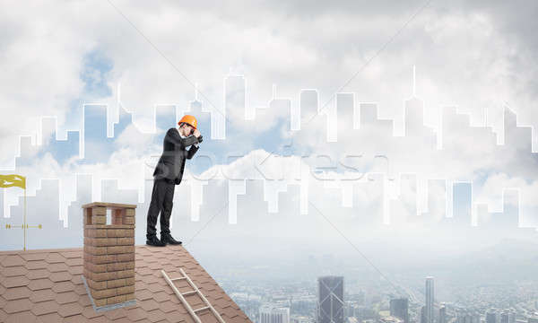 Engineer man standing on roof and looking in binoculars. Mixed media Stock photo © adam121