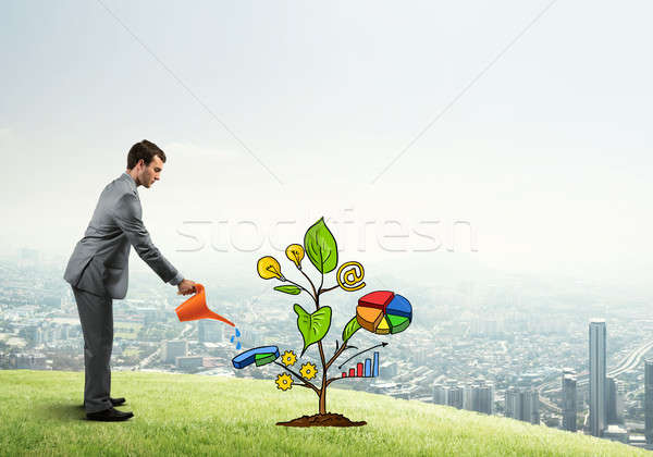 Young businessman outdoors watering drawn growth concept with can Stock photo © adam121