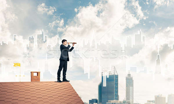 Stock photo: Engineer man standing on roof and looking in spyglass. Mixed med