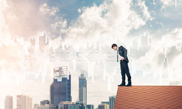 Businessman looking down from roof and modern cityscape at backg Stock photo © adam121