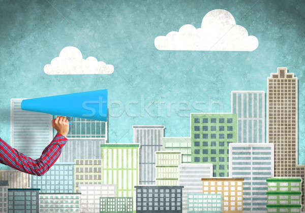 Stock photo: Hand of woman holding blue paper trumpet against illustrated background