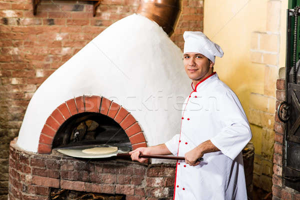 Chef puts dough in the oven for pizzas, Stock photo © adam121