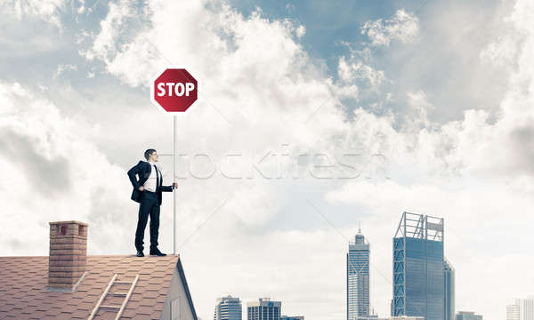 Caucasian businessman on brick house roof showing stop road sign Stock photo © adam121