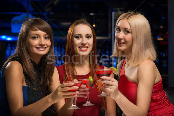 Stock photo: three girls raised their glasses in a nightclub